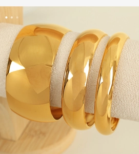 Detailed view of three polished gold titanium steel bangles in varying widths on a roll