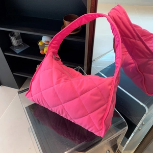 Pink quilted nylon pillow bag on acrylic stand showcasing smooth fabric texture and handle