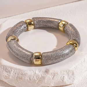 Detail of silver glitter tube bracelet with polished gold metal beads on white stone