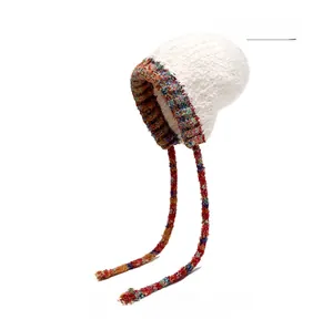 Vue détaillée du bonnet en peluche beige avec bord tissé coloré et attaches cache-oreilles
