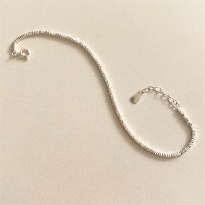 Detailed close-up of a silver beaded chain bracelet with adjustable extension and drop charm