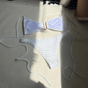 Detail of white bikini with U-shaped gold hardware and textured wavy fabric finish