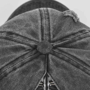 Macro view of washed charcoal cotton baseball cap featuring top button and vintage distressing