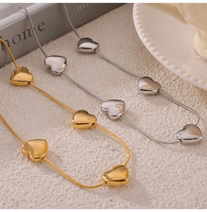 Detail of heart pendant necklaces in gold and silver finish with fine snake chains
