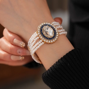 Macro detail of multi-layer pearl bracelet with a blue enamel oval gemstone clasp on wrist