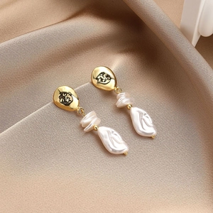 Macro detail of long baroque pearl earrings with irregular gold plating on silk background