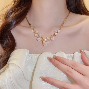 Detail of multi-layer gold necklace featuring pearl accents and a light pink resin flower