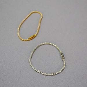 Close-up of gold and silver tennis bracelets with cubic zirconia and folding clasps