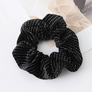 Detailed view of black velvet scrunchie with silver polka dots and pleated texture