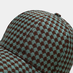 Macro detail of houndstooth plaid baseball cap showing woven blue and brown fabric texture