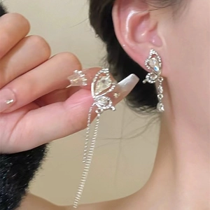 Detailed view of silver bow earrings with elegant tassel chains and sparkling rhinestones