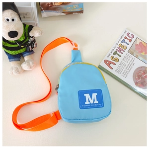 Détail du sac bandoulière enfant en nylon bleu et orange avec écussons tendance