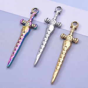 Three punk sword pendants in rainbow, silver, and gold finishes on a minimalist background
