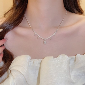 Close-up of elegant flower pendant necklace with zircon and pearls on woman neck