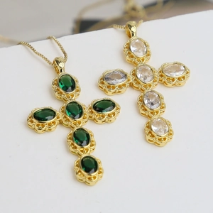 Elegant gold cross necklace with micro-paved green zircon pendant on white stairs