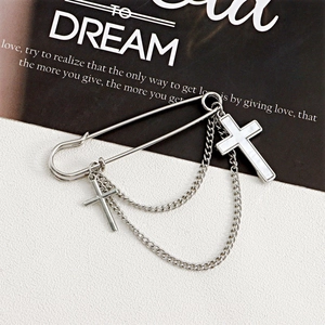 Detail of silver cross brooch with white shell pendant and layered metal tassel chains
