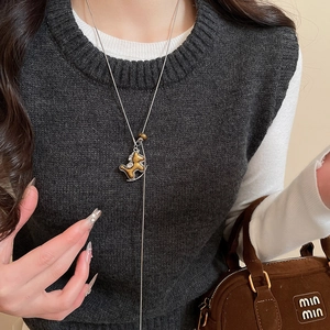 Détail du collier pendentif cheval à bascule marron sur une chaîne argentée porté par un mannequin