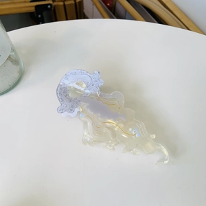 Detail of jellyfish-shaped acetate hair claw with iridescent finish and gold accents