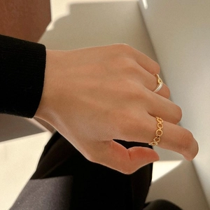 Close-up of elegant gold beaded ring and thin band worn on finger with minimalist shadow