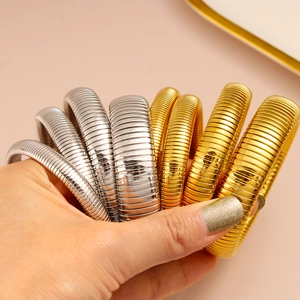 Primer plano de brazaletes de resorte flexibles chapados en oro de 18K y plata para mujer