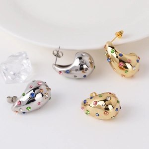 Dettaglio di orecchini a goccia in oro e argento con zirconi multicolore incastonati