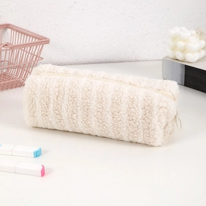 Close-up of plush cylindrical pencil case in cream beige with soft faux fur texture