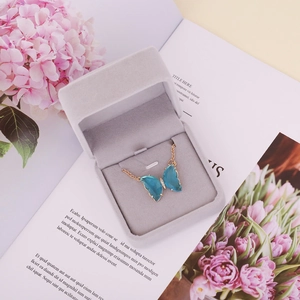 Blue glass butterfly pendant with crystals on a gold chain in a jewelry box