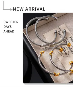Macro detail of twisted cable bangles featuring X-shaped accents and polished end caps