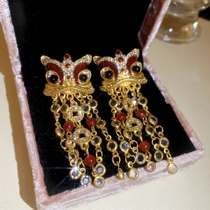 Détail de boucles d'oreilles danse du lion dorées avec glands et pierres précieuses
