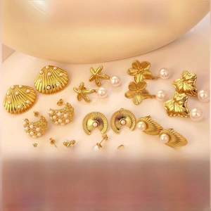 Detailed close-up of gold-plated titanium earrings with pearl shell and star designs