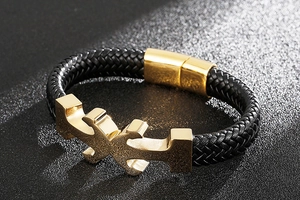 Close-up of golden anchor magnetic buckle and black woven leather rope bracelet