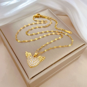 Luxurious gold heart angel wing necklace with sparkling zircons on a beige silk display