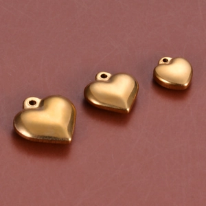 Detailed view of three golden stainless steel heart charms in varying sizes for DIY jewelry