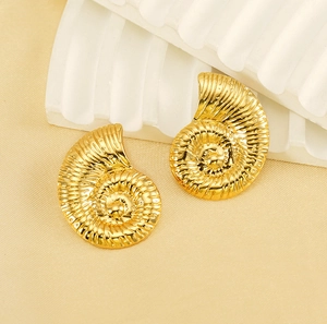Macro detail of gold conch-shaped earrings with fine radial textures on fabric