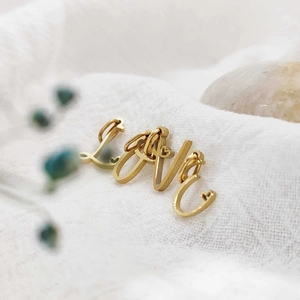 Close-up of 14K gold plated stainless steel Love letter charms for DIY jewelry making.