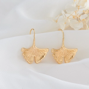 Elegant 14K gold-plated ginkgo leaf hook earrings with brushed texture on white fabric