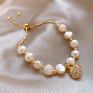 Detail van vergulde armband met zoetwaterparels en zirkonia schelphanger op zijde
