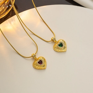 Detailed view of 18k gold heart pendants with red and green gemstones and textured edges