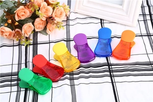 Dettaglio di clip colorate multifunzionali per alimenti su uno sfondo a quadretti bianco e nero