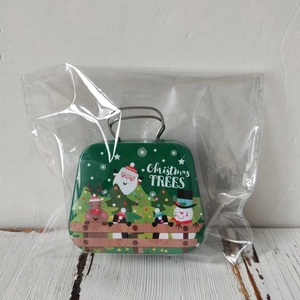 Detail of green Christmas tin suitcase box with metal handle and holiday illustrations