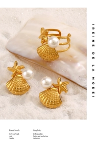 Dettaglio del set gioielli con conchiglie e stelle marine con perle su sabbia bianca