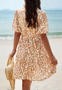Back view of a summer dress with geometric prints on a beach background with waves