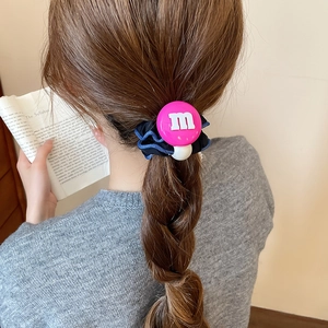Détail d'un chouchou en tissu bleu foncé avec lettre M en résine rose et perle blanche