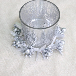 Silver Christmas wreath napkin ring with glass candle holder on white plush fabric