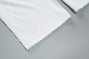 Detailed close-up of white ribbed knit fabric texture and double-needle stitching quality