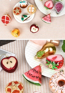 Close-up of painted glass Christmas ornaments in fruit and food shapes with glitter