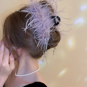 Detail of purple feather hair claw with sparkling rhinestone tassels on a hair bun