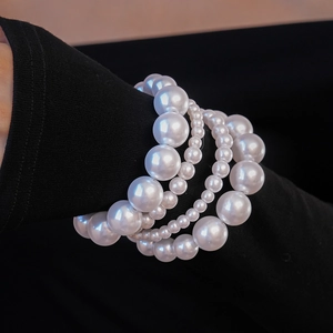 Gros plan de bracelets multicouches en perles d'imitation sur une manche noire