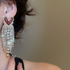 Detail shot of heart-shaped earrings with red rhinestones and long silver tassels
