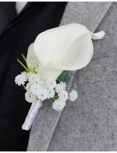 Detail of white calla lily boutonniere with satin ribbon on a grey suit jacket
